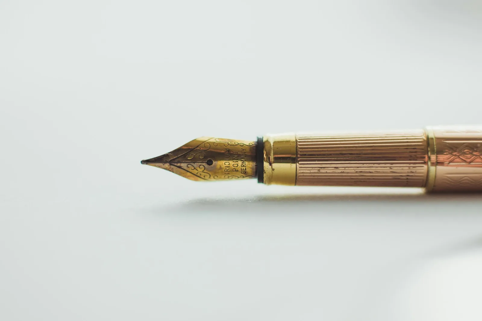 Plume dorée d'un stylo posé sur une surface blanche